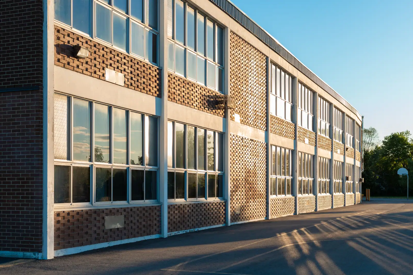 The brick and glass facade of a two-storey school building in evening light.