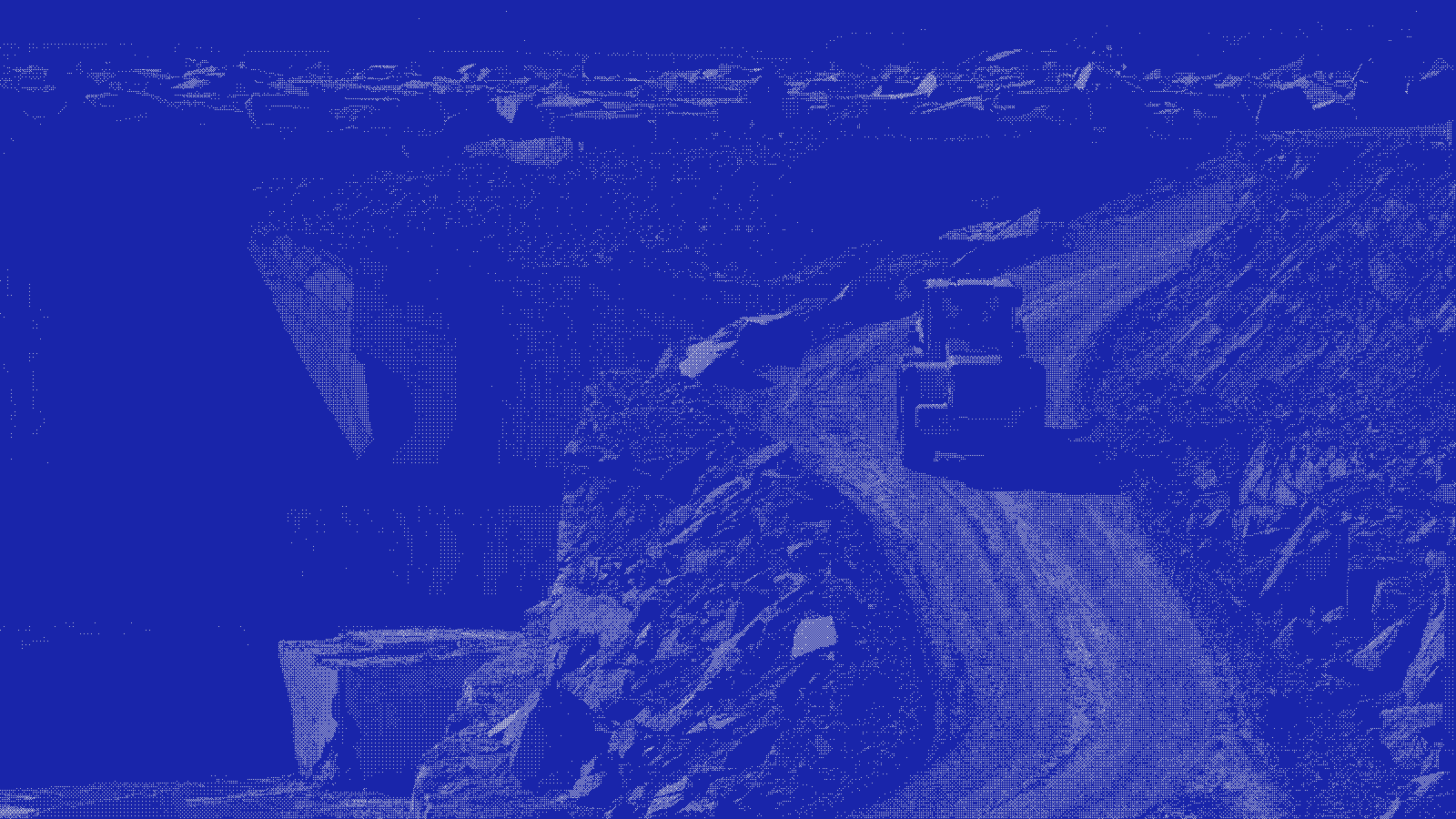 A loader on a haul road through an open-cut quarry, rendered as a blue two-tone dither pattern